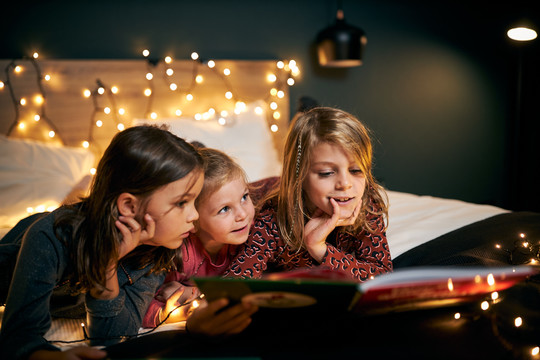 Kinder lesen ein Buch im Bett